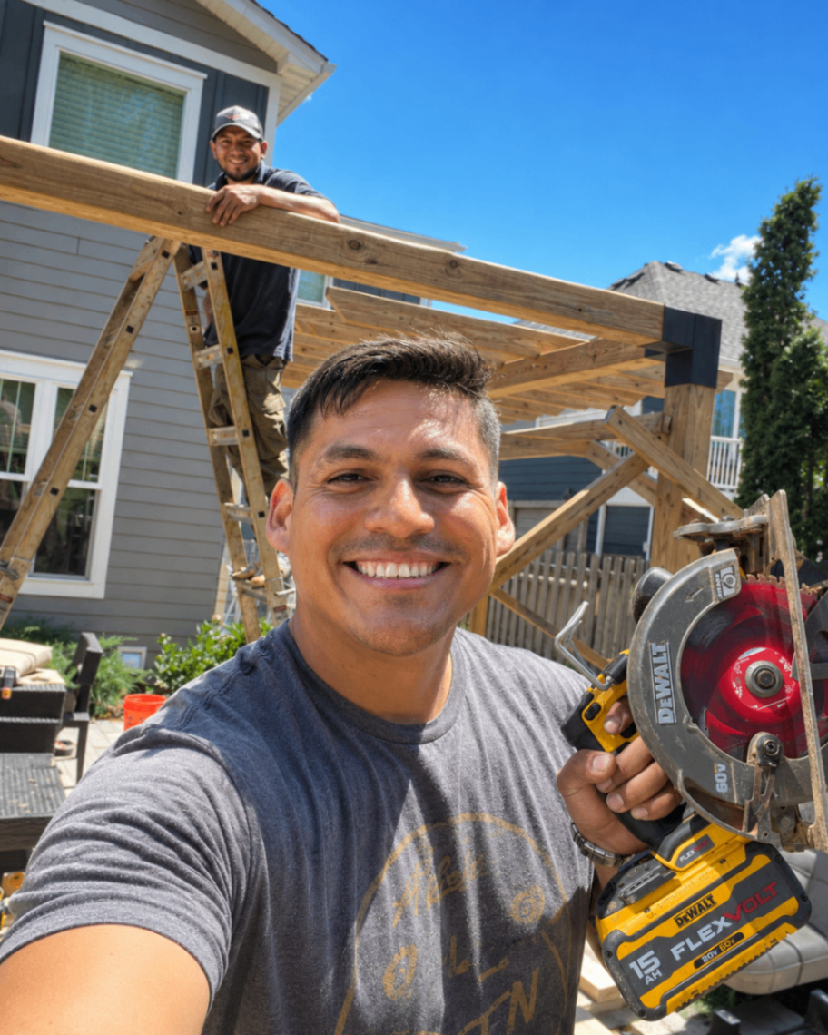 Eddie Osorio smiling on a job site with a DeWalt saw, pergola frame behind him